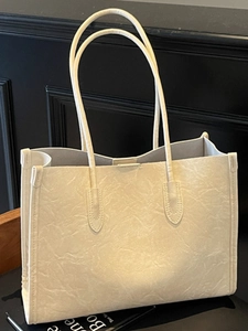 Retro cream white oversized tote bag with pleated texture on a dark wooden background