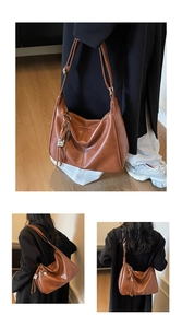 Détail d'un grand sac hobo marron avec pompon tressé et bandoulière en cuir réglable