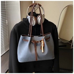 Detail of gray canvas tote bag with brown leather straps and ethnic wooden bead charm