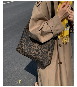 Street style view of a large leopard print tote bag paired with a classic trench coat