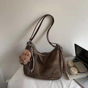 Detail of vintage brown leather tote bag with teddy bear charm and silver brand plate