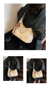 Détail d'un grand sac hobo crème avec breloque ours brun porté par un mannequin en studio