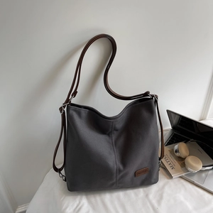 Detail view of deep gray canvas tote bag with brown leather straps in a home office setting