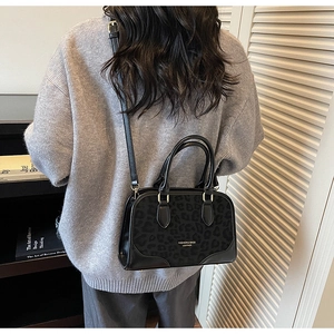 Macro detail of black leopard print Boston bag styled as a crossbody on a female model