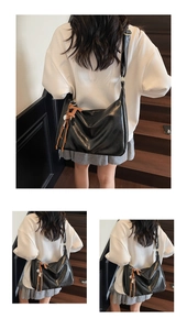 Détail d'un grand sac cabas en cuir noir avec pompon orange porté par un mannequin