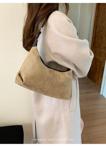 Detail showing the minimalist brown suede shoulder bag with adjustable black strap