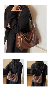 Détail du grand sac cabas en cuir souple marron avec pompons et large bandoulière