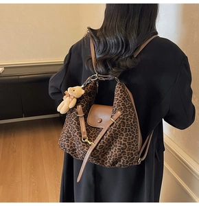 Detail eines Rucksacks mit Leopardenmuster, brauner Lederklappe und Plüschbär-Anhänger