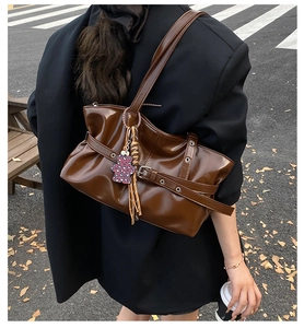Détail du sac à bandoulière marron plissé avec œillets métalliques et breloque ours