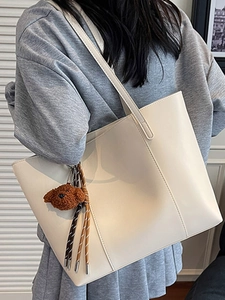Minimalistische beige große Tragetasche mit vertikalen Nähten und Bärenanhänger