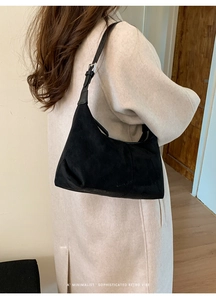 Detail shot of black minimalist suede hobo bag with adjustable strap and metal hardware