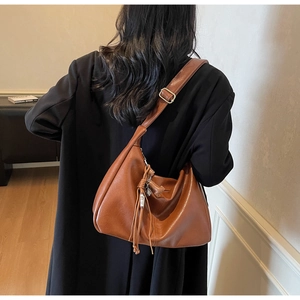 Sac hobo en cuir marron avec franges et boucle argentée porté par un mannequin