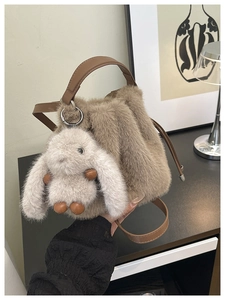 Vue détaillée de la texture du sac seau en peluche marron avec un porte-clés lapin