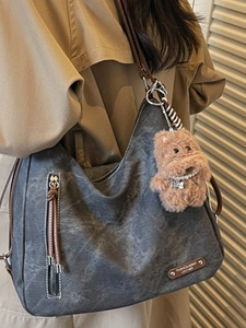 Deep grey vintage tote bag with brown leather straps and plush puppy charm accessory
