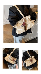 Gros plan sur le sac à bandoulière beige brillant avec boucle en métal et charm cœur léopard