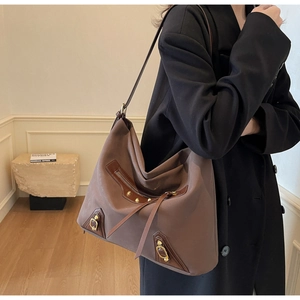 Detailed close-up of brown vintage hobo bag with industrial metal rivets and zippers