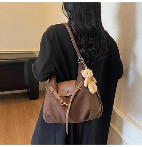Braune Wildleder-Einkaufstasche mit Lederklappe und Teddybär-Anhänger am Model