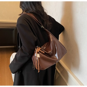 Gros plan sur la texture du cuir marron foncé, la boucle en métal et le gland décoratif