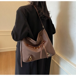 Detail of vintage coffee hobo bag with gold rivets and long tassels on shoulder
