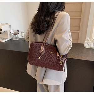 Détail d'un sac cabas léopard avec lettrage doré présenté dans un cadre de café chic