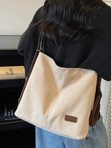 Large beige canvas tote bag with brown leather straps shown from a model's back view