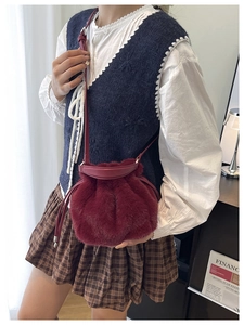 Gros plan d'un sac seau en peluche bordeaux avec texture en fausse fourrure et cordon