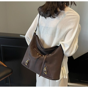 Detail view of large dark brown tote bag with retro metallic rivets on shoulder strap