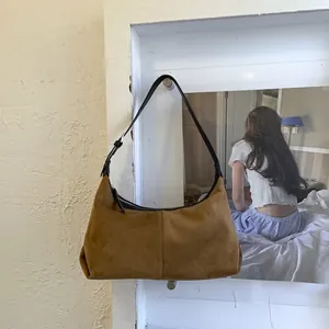Detail of brown faux suede hobo bag featuring black shoulder strap and silver metal buckle