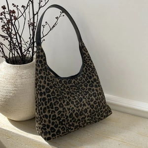 Detail of leopard print hobo bag showing the wide black leather strap and textured fabric