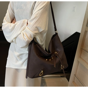 Detail of dark brown leather hobo bag with vintage gold rivets and metallic hardware