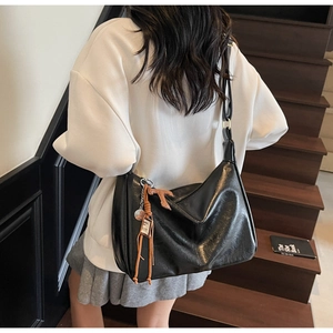 Gros plan sur un sac cabas en cuir noir avec de longues franges et des détails métalliques