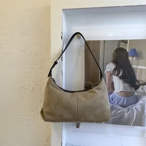 Detail of khaki suede hobo bag with slim black leather strap and minimalist half-moon shape