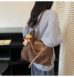 Detailansicht der Hobo-Tasche mit Leopardenmuster, braunem Riemen und Plüschbär-Anhänger