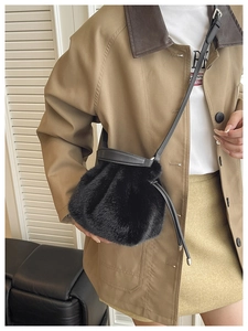 Détail d'un sac seau en fausse fourrure noire avec fermeture à cordon et bandoulière