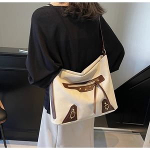 Detail of canvas tote bag featuring brown leather trim, metal rivets and long tassels