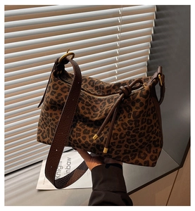 Detail of leopard print canvas tote bag featuring brown leather strap and gold metal hardware