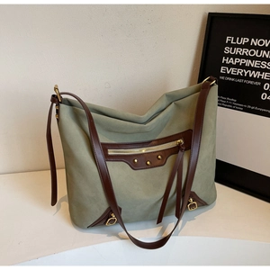 Detail of sage green suede tote with brown leather trim, metal studs and long tassels
