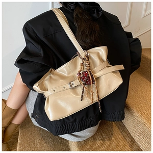 Détail du sac à bandoulière plissé beige avec fini brillant et breloque cœur léopard