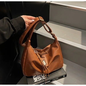 Détail du sac bandoulière en similicuir marron avec plis et ornement de pompon
