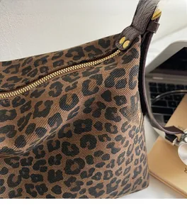 Detail of leopard print fabric texture and premium gold metal zipper on tote bag