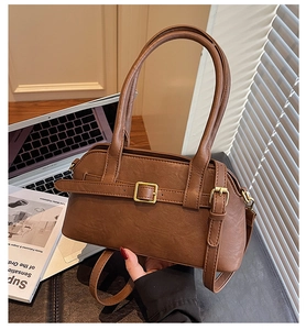 Close-up of brown retro shoulder bag with golden metal buckles and slender straps