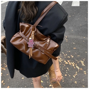 Détail d'un sac à bandoulière marron brillant avec boucles et breloque ours léopard