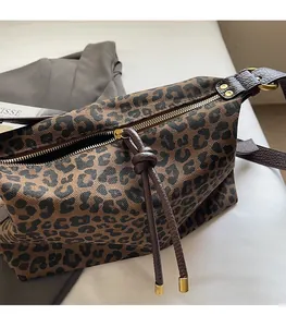 Detail of leopard print canvas bag featuring golden zipper with leather woven puller knot