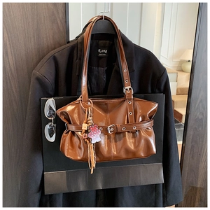 Détail d'un sac cabas plissé marron avec boucle de ceinture et charm d'ours à pois rouges