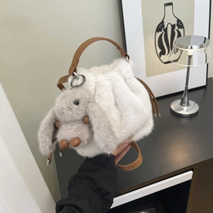 Détail d'un sac seau en fausse fourrure blanche avec bandoulière en cuir brun et lapin