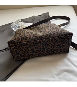Detail showing leopard print canvas texture with adjustable brown strap and gold metal buckle