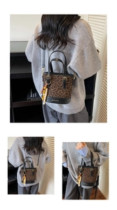 Detail of leopard print bucket bag featuring wooden bead charm and metal lock hardware