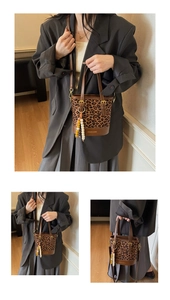 Detail of leopard print bucket bag featuring brown handle and beaded charm accessory