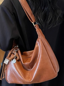 Sac fourre-tout en cuir marron rétro avec large bandoulière porté par un mannequin