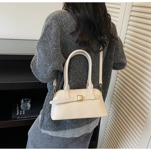 Close-up of minimalist white shoulder bag with gold buckle on grey knit dress